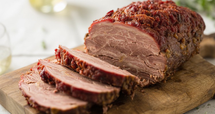 Sliced smoked meatloaf on a cutting board showing juicy interior smoke ring and glazed exterior crust