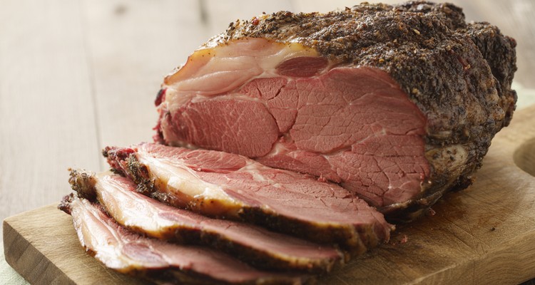 Smoked Ribeye Roast — Juicy, Tender, and Reliable Results Sliced smoked ribeye roast showing a juicy pink interior and dark crusty bark on a cutting board
