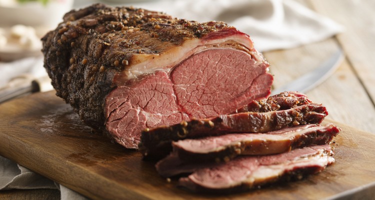 Sliced smoked ribeye roast on a cutting board with dark bark and pink interior Sliced smoked ribeye roast on a cutting board with dark bark and pink interior