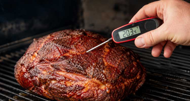 Checking smoked pork temperature with a probe thermometer